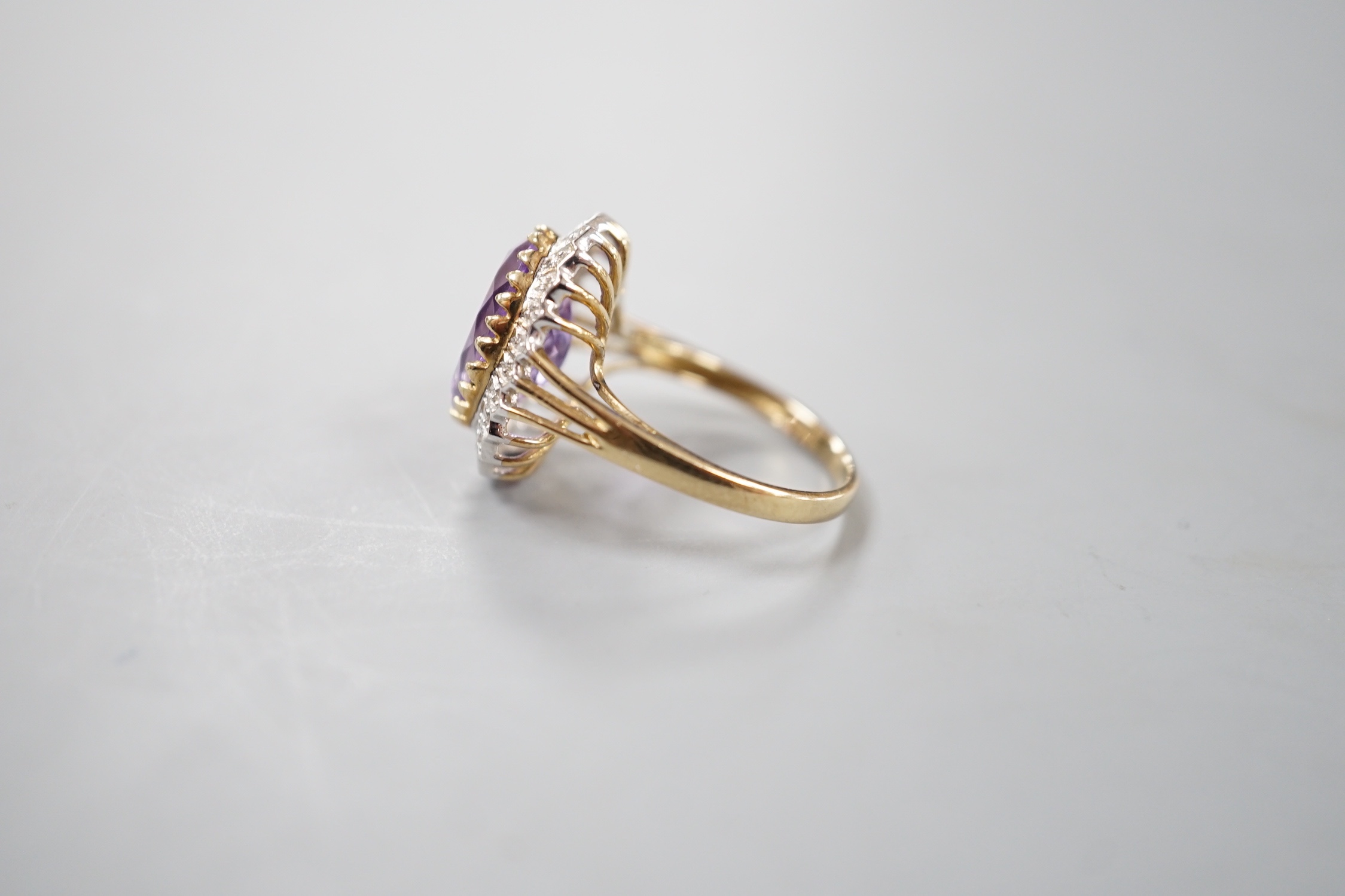 A modern 9ct gold, amethyst and diamond chip set oval cluster ring, size Q, gross weight 4.6 grams.